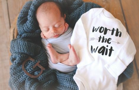 Newborn Gus alongside his 'worth the wait' onesie